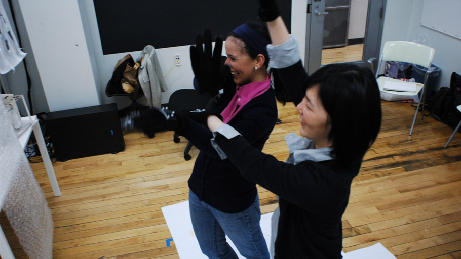 Two users of tangle laugh and smile while moving their hands together