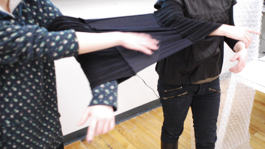 Two users wear a uniquely designed sleeve-garment to link their arms together and constrain their movement while using tangle